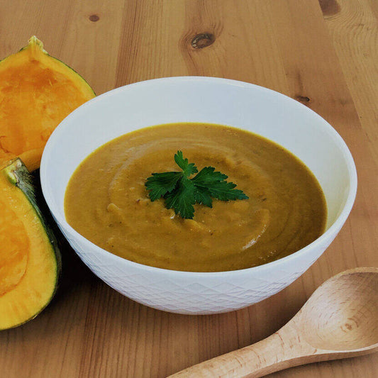 Geometric bowl with squash-lentil soup, herbs, wooden spoon.